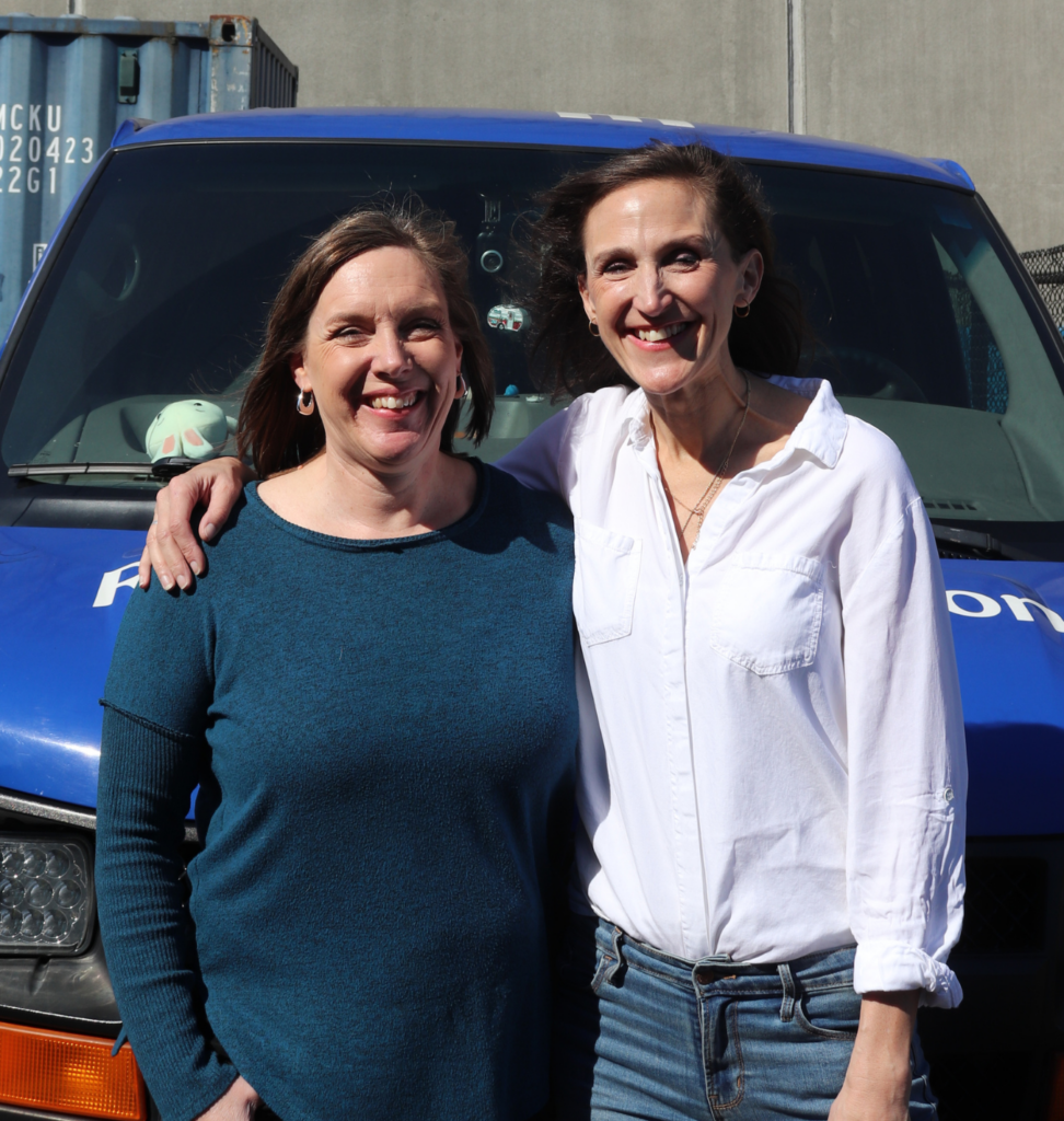 Volunteers Diane (left) and Jeannine (right) pose for a photo standing in front of the Tacoma Rescue Mission Search and Rescue van.